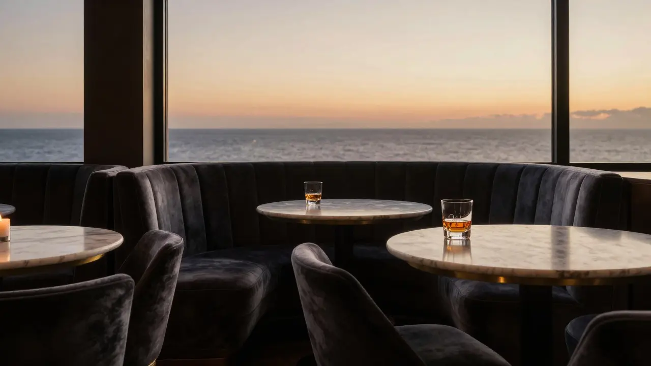 Empty luxury bar at sunrise with a single whiskey glass by a window overlooking the Mediterranean Sea.