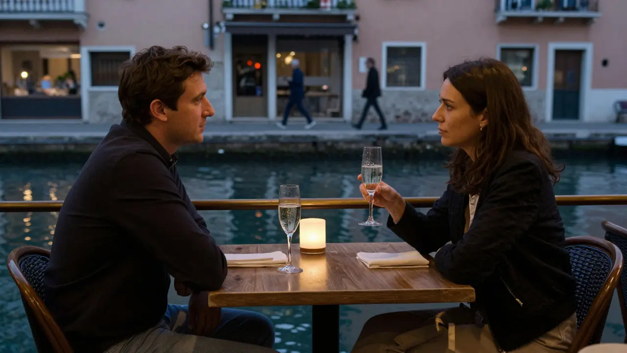 Two people enjoy prosecco at a café table in Navigli, the canal reflecting soft evening light.